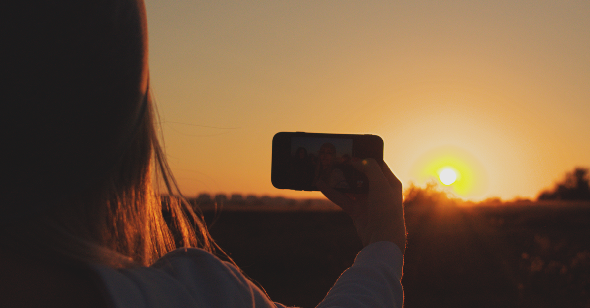 Persona sosteniendo un teléfono frente al rostro para un selfie